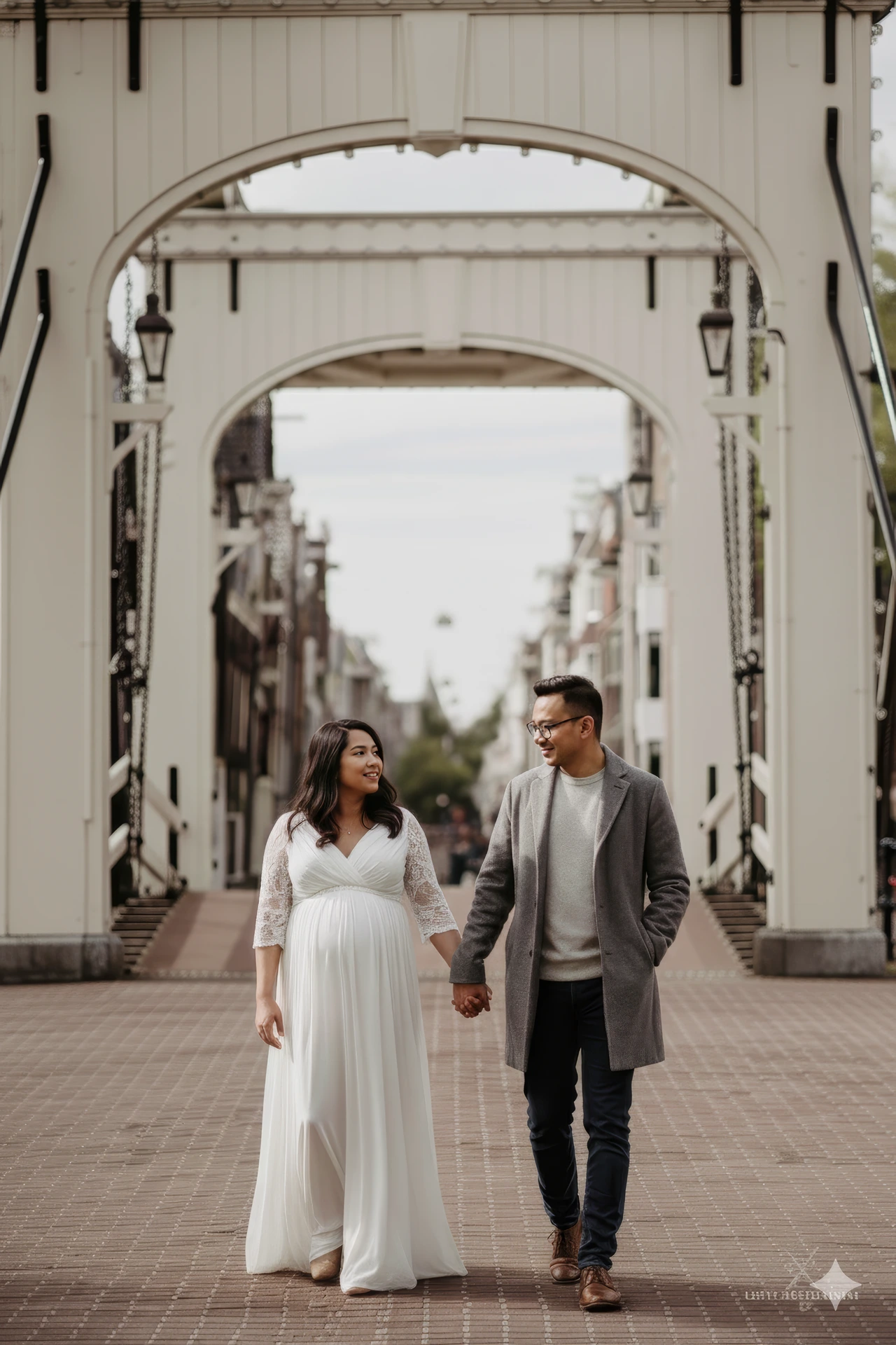 Een fotograaf die een fotoshoot doet bij de Magere Brug in Amsterdam met een koppel dat wandelt
